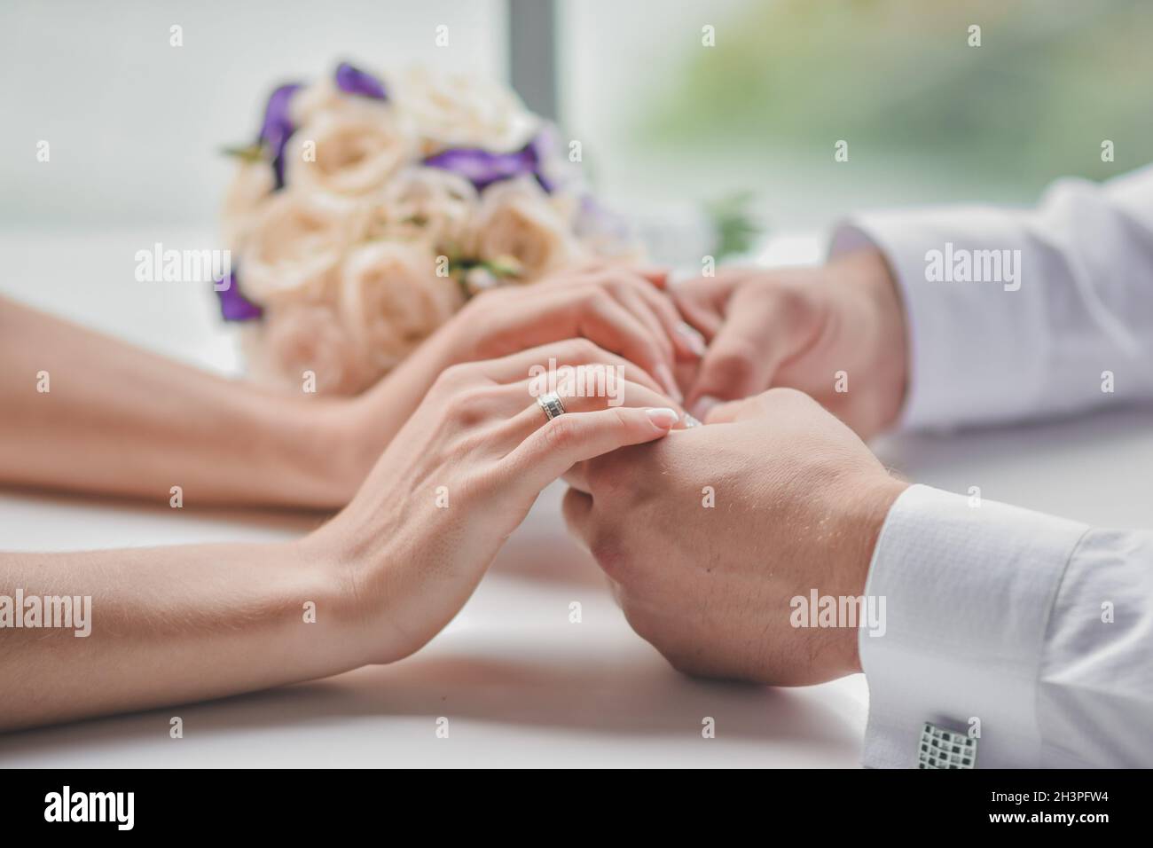 Le mani maschili tengono le mani femminili. L'uomo ha dato fiori alla donna. Primo piano. Senza un volto. Foto Stock