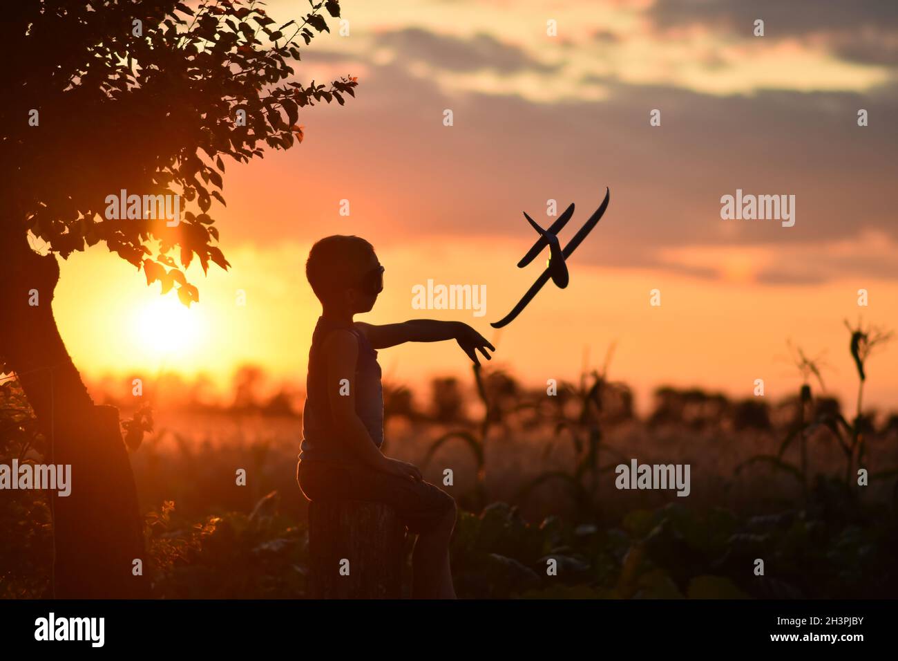 Il ragazzo lancia l'aereo in volo al tramonto. Foto Stock