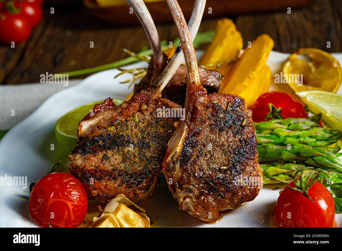 Costolette di agnello marinate in erbe con asparagi verdi e lime Foto Stock