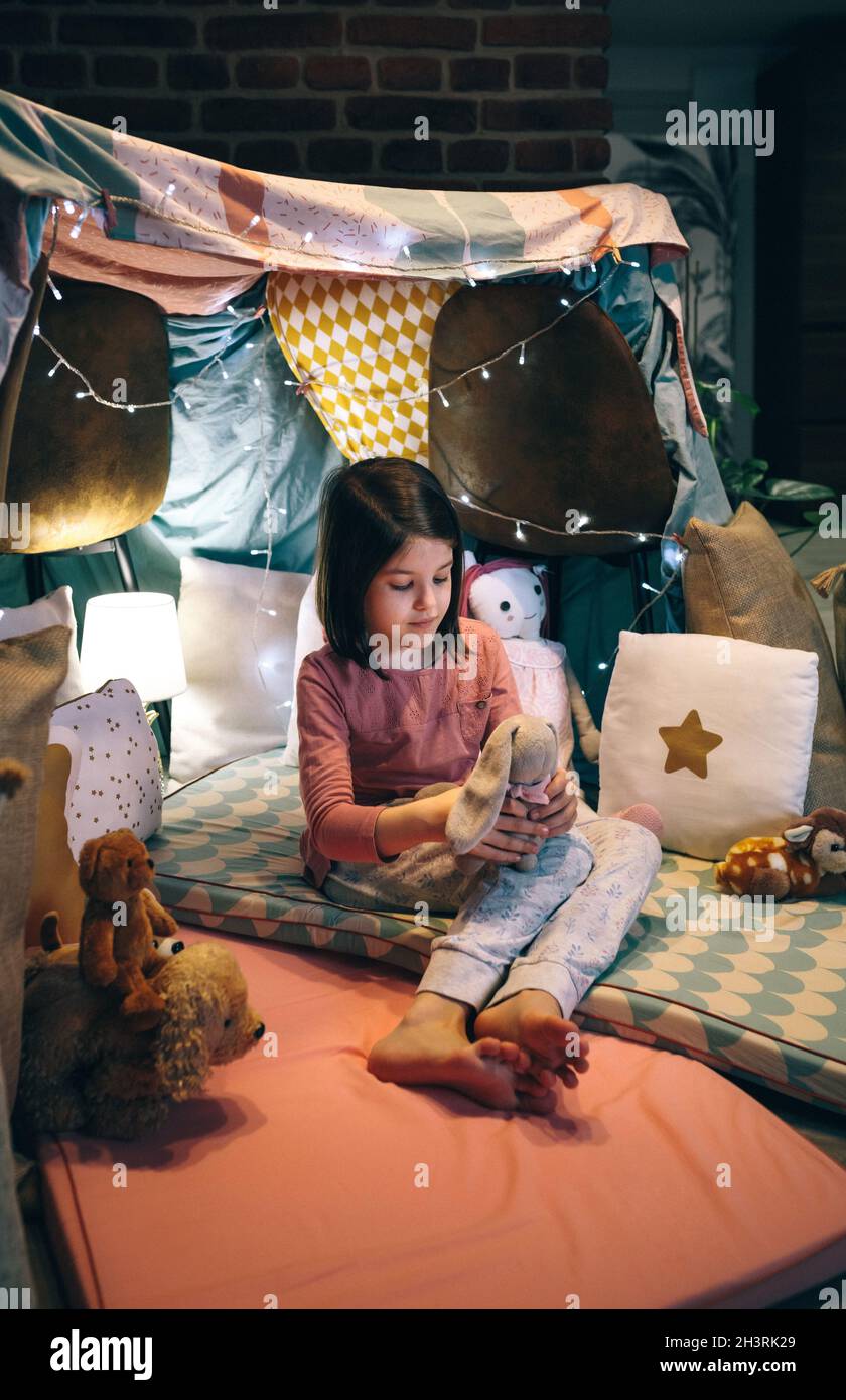 Ragazza in pigiama giocando con coniglietto imbottito in un teepee Foto Stock