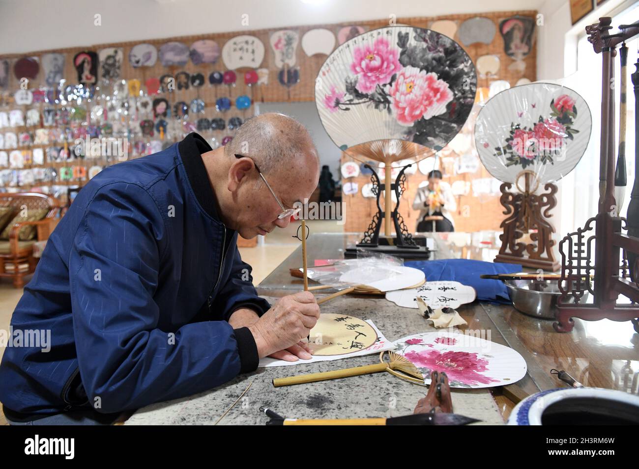 Lingchuan, Cina. 29 ottobre 2021. (211030) -- LINGCHUAN, 30 ottobre 2021 (Xinhua) -- Huang Shuofu, un erede di Guilin bambù circolare tecnica di fabbricazione del ventilatore, scrive su un ventilatore in Dingjiang Township di Guilin, la regione autonoma di Guangxi Zhuang della Cina del sud, 29 ottobre 2021. Fare di un tale ventilatore non è un compito semplice, gli artigiani tagliano il bambù ammollato in dozzine di strisce per fare il telaio del ventilatore, incollano la superficie con carta di Xuan, stoffa di cotone e seta, infine fanno il ventilatore circolare attraverso taglio e bordo che avvolge, e una buona pittura e/o calligrafia scrittura lo rende un elemento popolare nel mar culturale Foto Stock