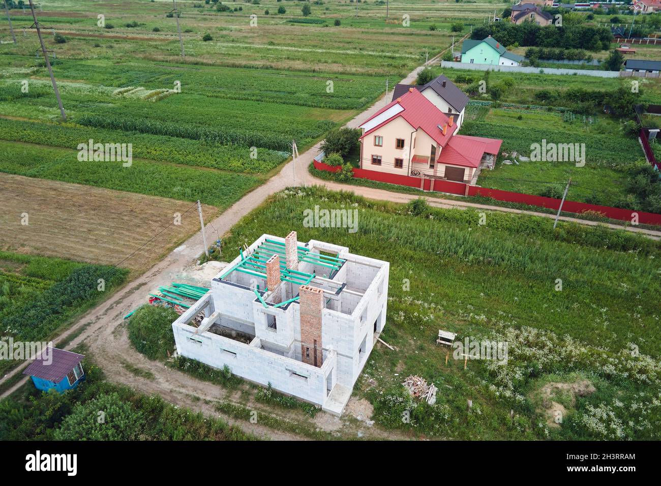 Vista aerea di telaio incompiuto di casa privata con pareti aerate in calcestruzzo leggero e travi in legno tetto in costruzione. Foto Stock