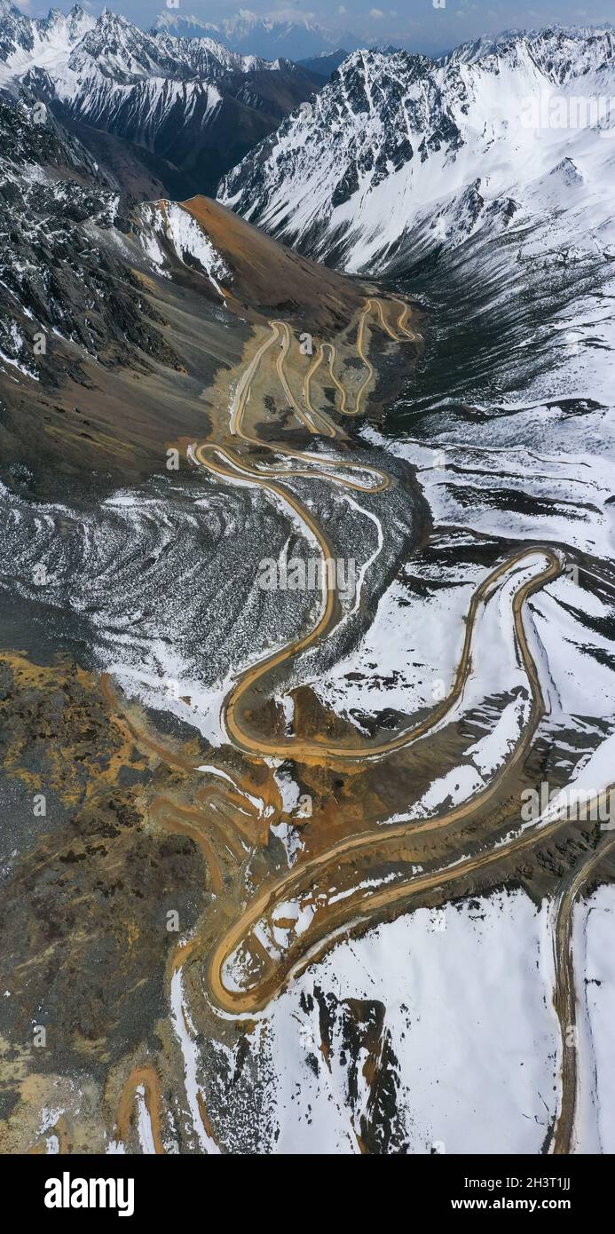 Vista aerea della tortuosa strada sterrata sulle montagne innevate Foto Stock