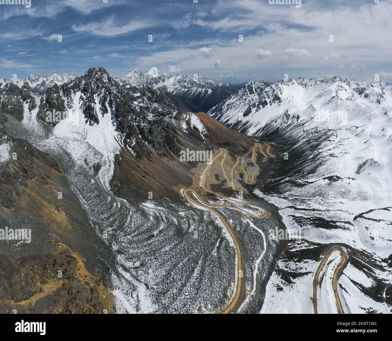 Tortuosa strada sterrata nelle montagne innevate Foto Stock