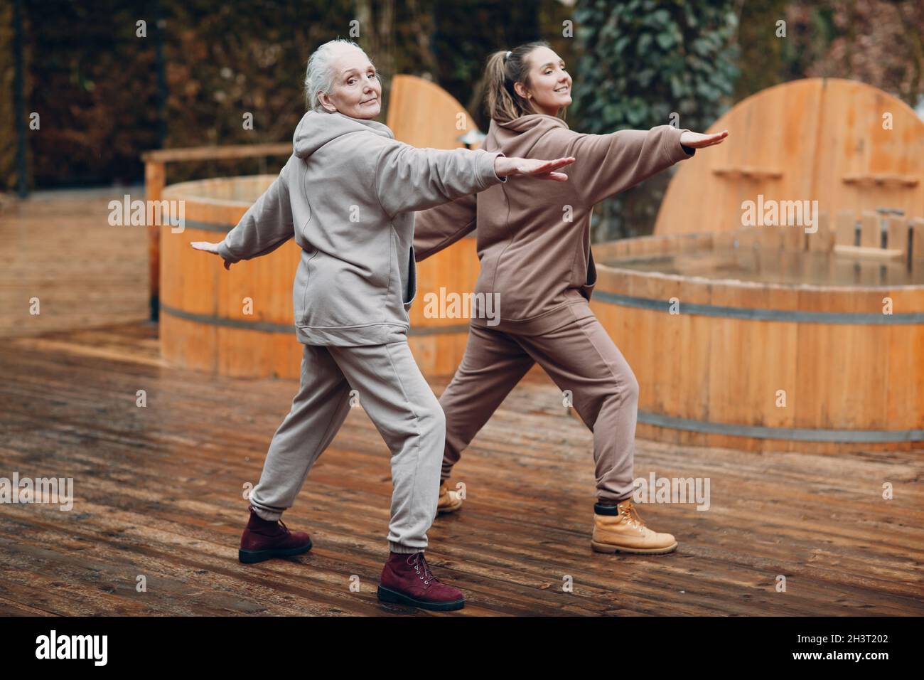 Donna giovane e anziana che si scalda e yoga si esercita all'aperto. Nonna e nipote che hanno zen come vacanza fitness moderna Foto Stock