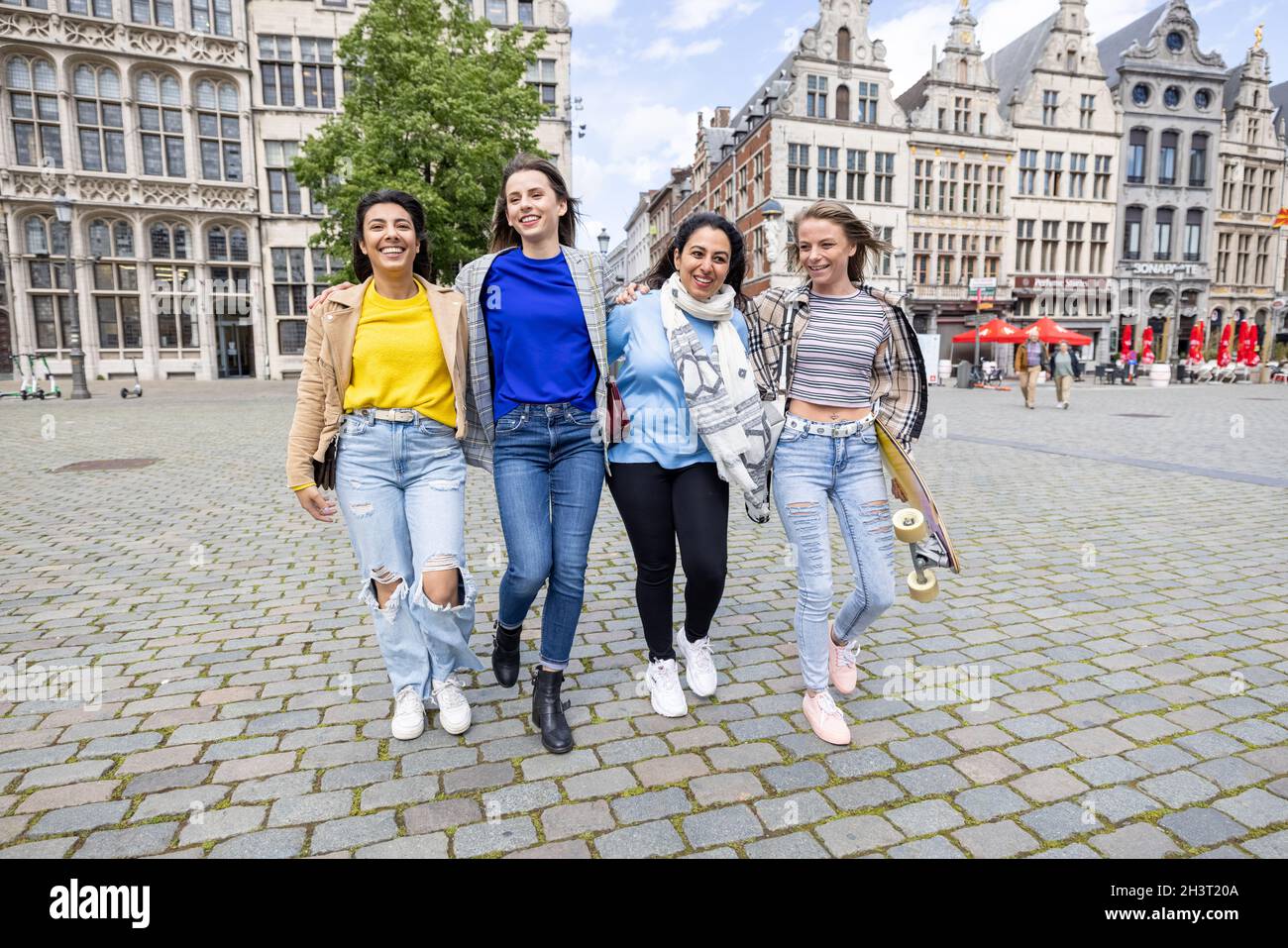 Ritratto lifestyle di un gruppo multietnico diversificato di quattro belle ragazze giovani girlfriends che camminano per una città europea e. Foto Stock