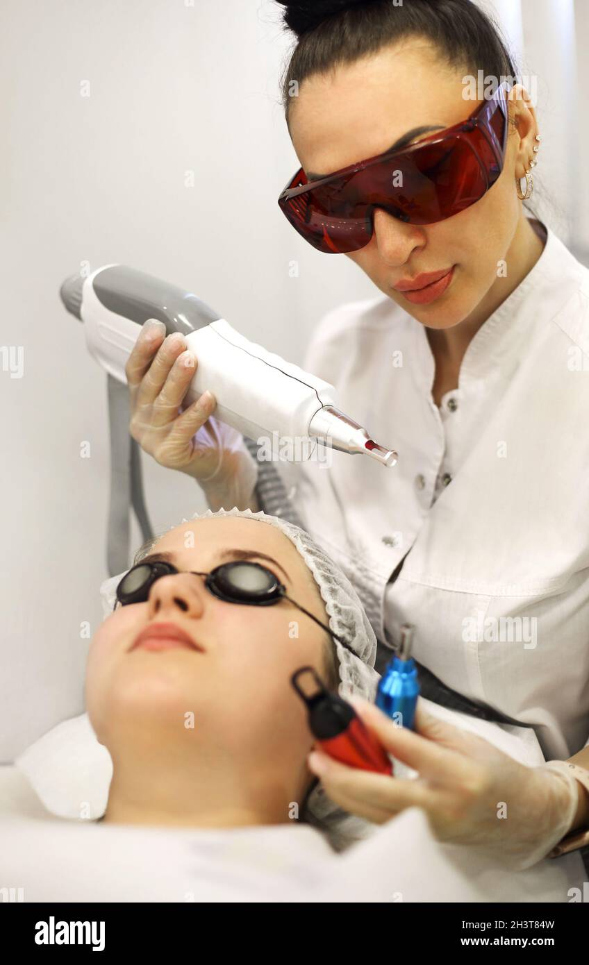 Donna che tratta il volto del cliente con il laser Foto Stock