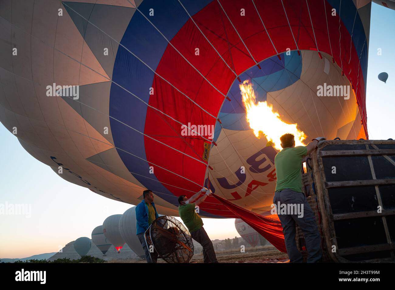 GOREME, TURCHIA - 3 AGOSTO 2021: Le persone lavorano sodo per gonfiare a terra un pallone ad aria calda utilizzando l'aria calda dalla fiamma del bruciatore in modo che il tour Foto Stock
