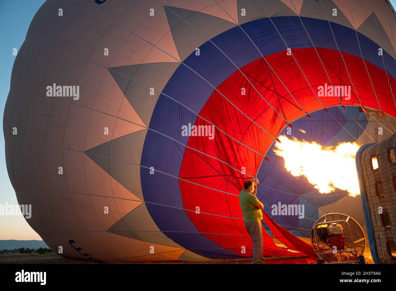 GOREME, TURCHIA - 3 AGOSTO 2021: Le persone lavorano sodo per gonfiare a terra un pallone ad aria calda utilizzando l'aria calda dalla fiamma del bruciatore in modo che il tour Foto Stock