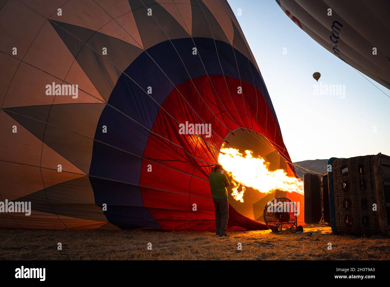 GOREME, TURCHIA - 3 AGOSTO 2021: Le persone lavorano sodo per gonfiare a terra un pallone ad aria calda utilizzando l'aria calda dalla fiamma del bruciatore in modo che il tour Foto Stock