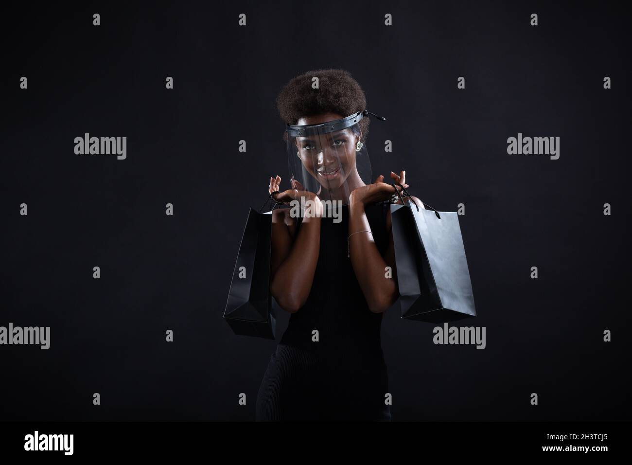 La donna afroamericana tiene i sacchetti neri di shopping. Vendita e sconti sul mercato e Black Friday Concept. Foto Stock