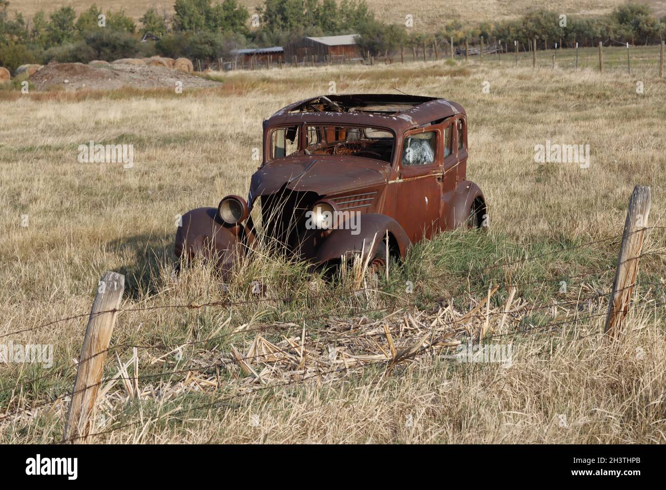 Un'auto d'epoca nel campo di un agricoltore come promemoria delle cose passate. Foto Stock