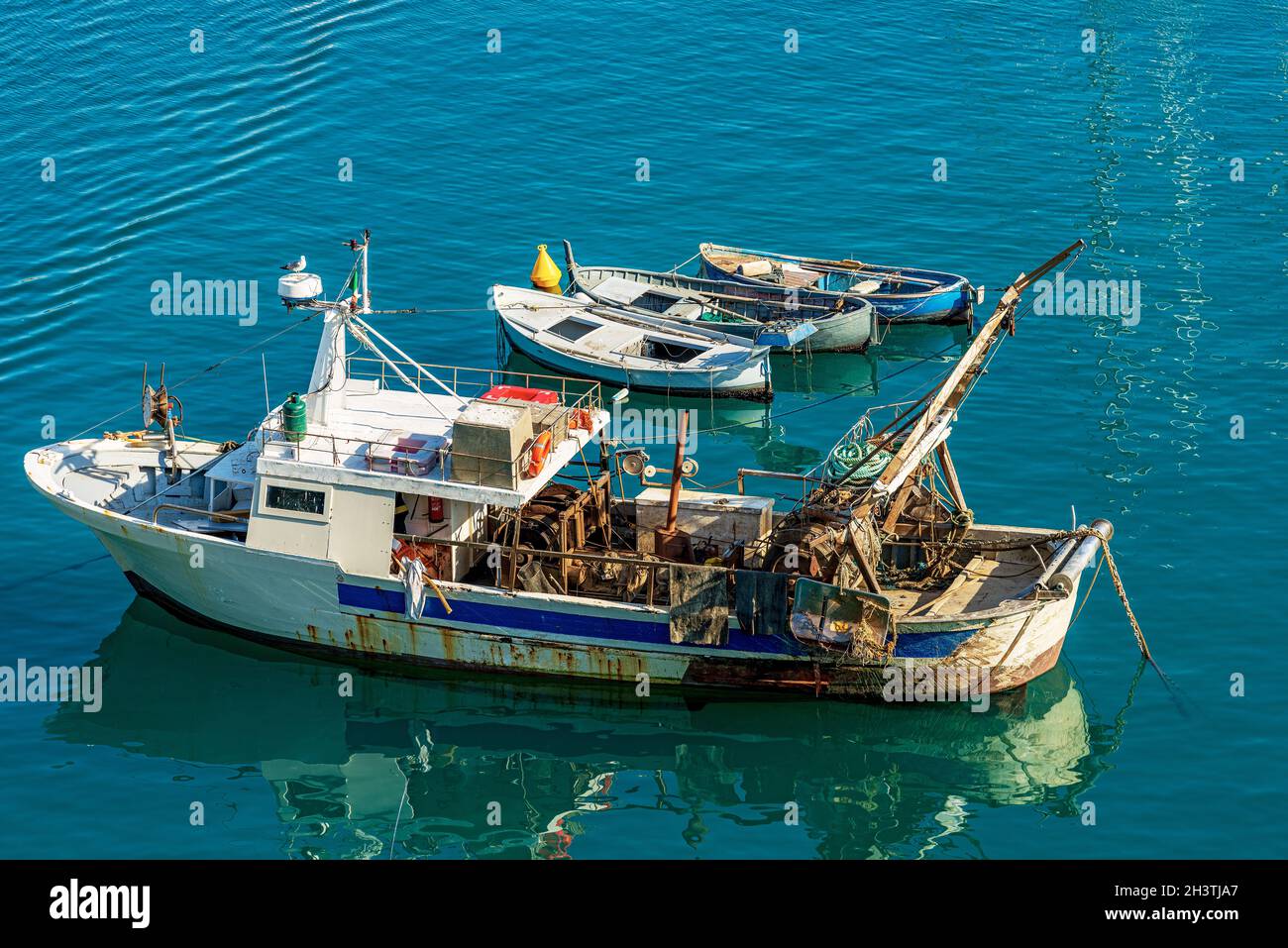 Vecchio peschereccio da traino e tre barche a remi in legno, ormeggiate nel Porto di Lerici, località turistica sulla costa del Golfo di la Spezia, Italia, Europa. Foto Stock