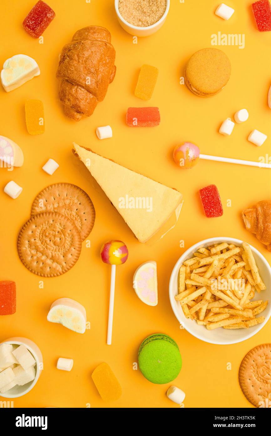 Zucchero nocivo dolce dolce per bambini modello su sfondo giallo chiaro. Foto verticale. Vista dall'alto, piatto. Dolce, dessert, dieta. Foto Stock