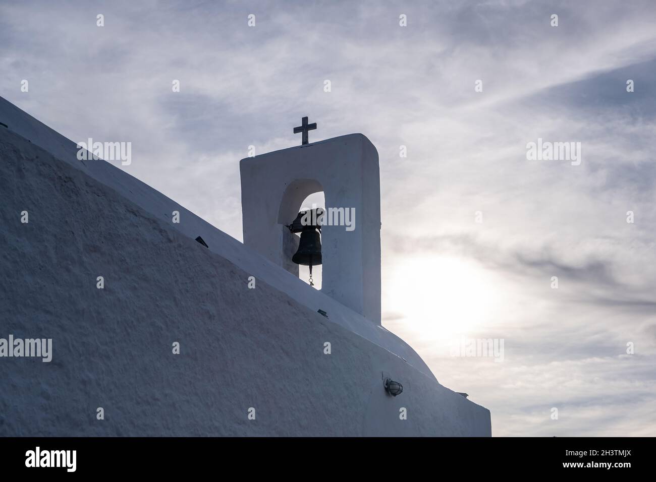 Isola di Serifos, Grecia. Piccola cappella antica, pareti bianche e campanile, chiesa greca ortodossa sulla collina rocciosa, cielo nuvoloso sfondo. Foto Stock