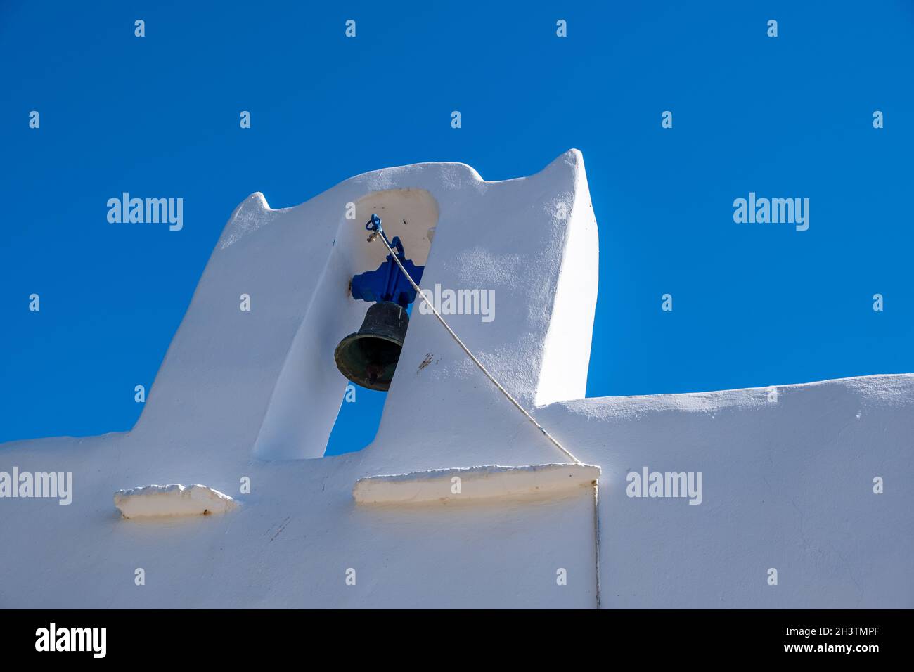 Campanile della Chiesa Ortodossa bianca con due campane. Parete bianca sullo sfondo blu chiaro del cielo. Isola di Sifnos, Cicladi Grecia. Foto Stock