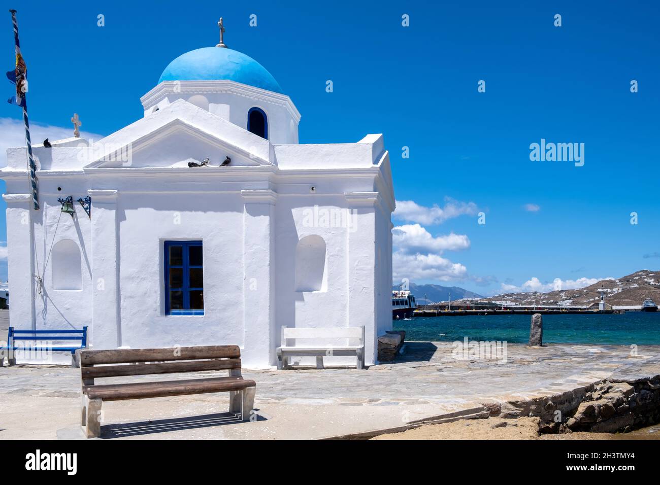 Chiesa con cupola blu nella città di Chora Mykonos isola, Cicladi. Grecia. Cappella bianca vicino al mare su sfondo cielo blu chiaro. Foto Stock