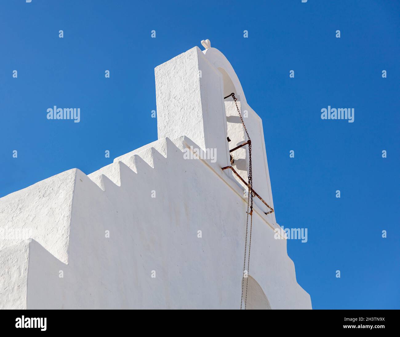 Tetto di cappella bianca a Kythnos isola Chora villaggio Cicladi destinazione religiosa Grecia. Belfry con vecchia catena campanaria al greco-ortodosso Christi Foto Stock