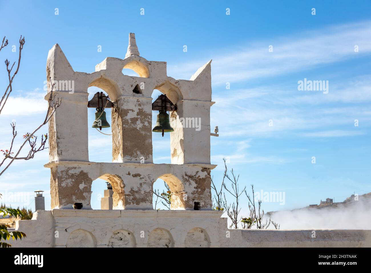 Campanile della Chiesa Ortodossa bianca con due campane. Muro imbiancato sullo sfondo blu del cielo. Isola di Sifnos, Cicladi Grecia. Foto Stock