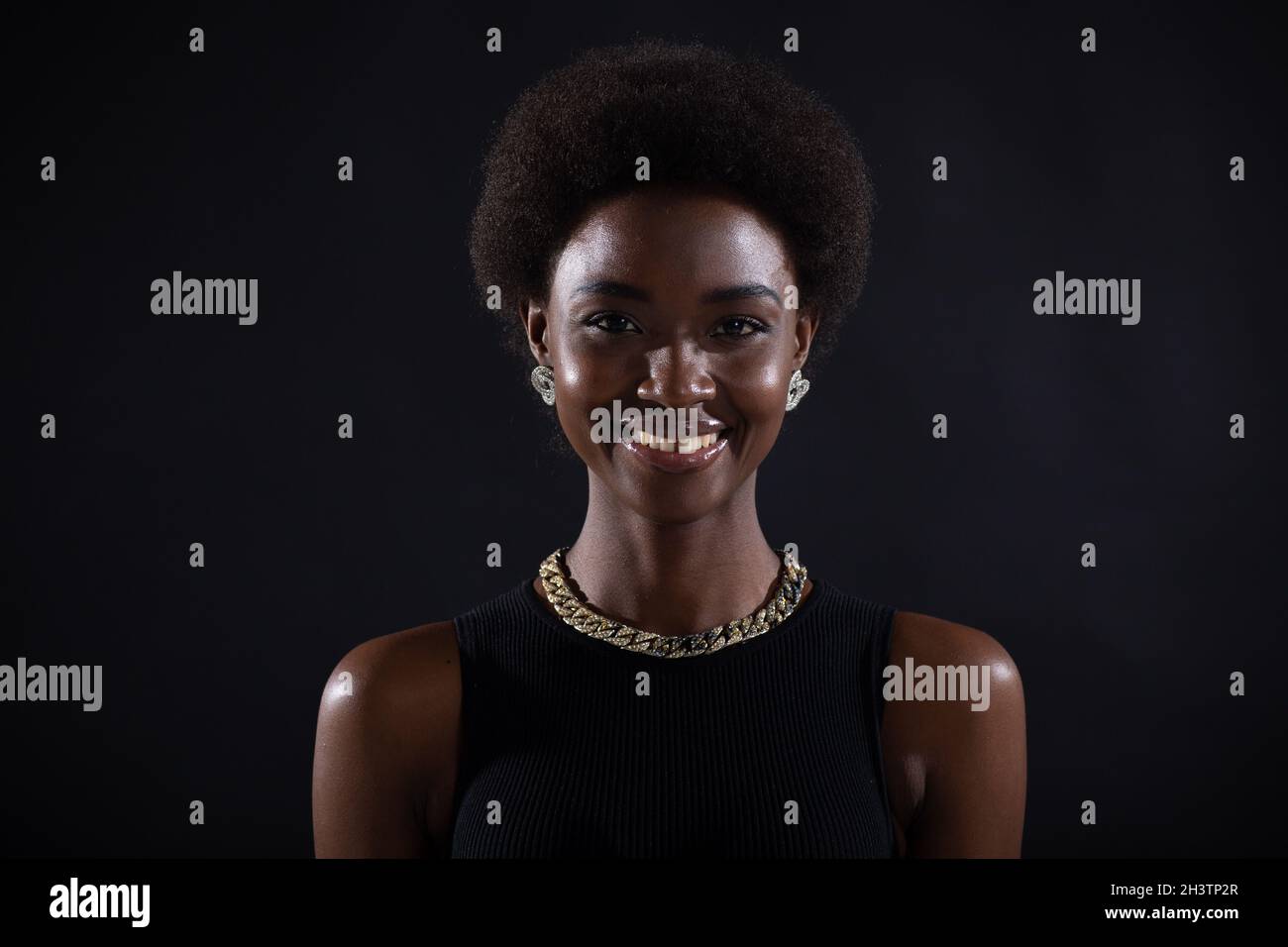 Primo piano ritratto di donna afroamericana con acconciatura afro su sfondo nero studio Foto Stock