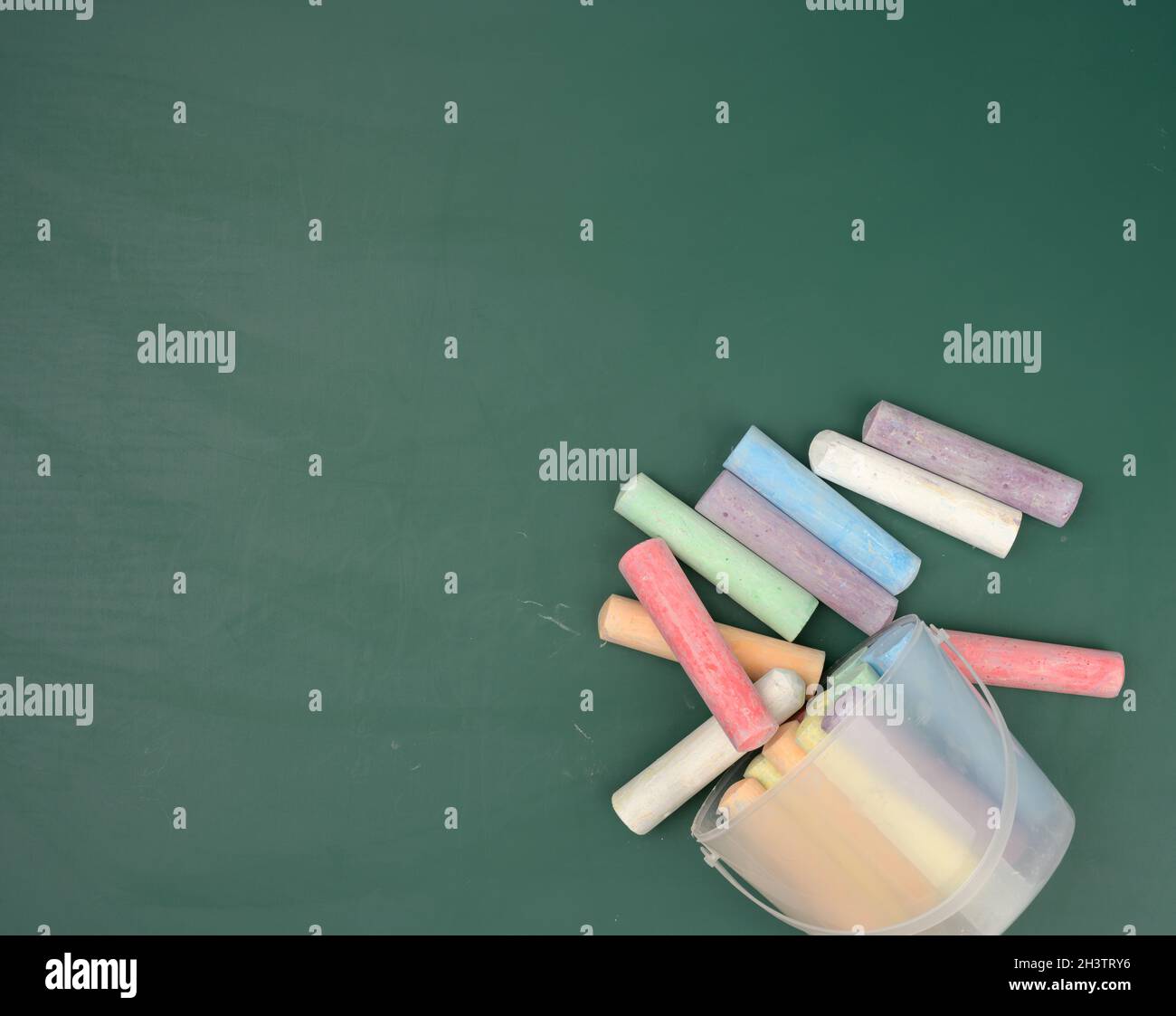 Pastelli multicolori sullo sfondo di una lavagna verde gesso scuola Foto Stock