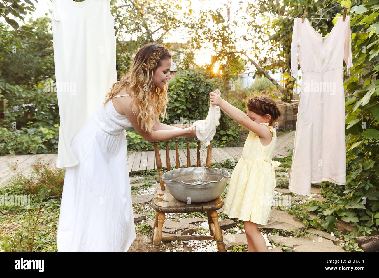 Madre e figlia appesi lavanderia in cortile Foto Stock