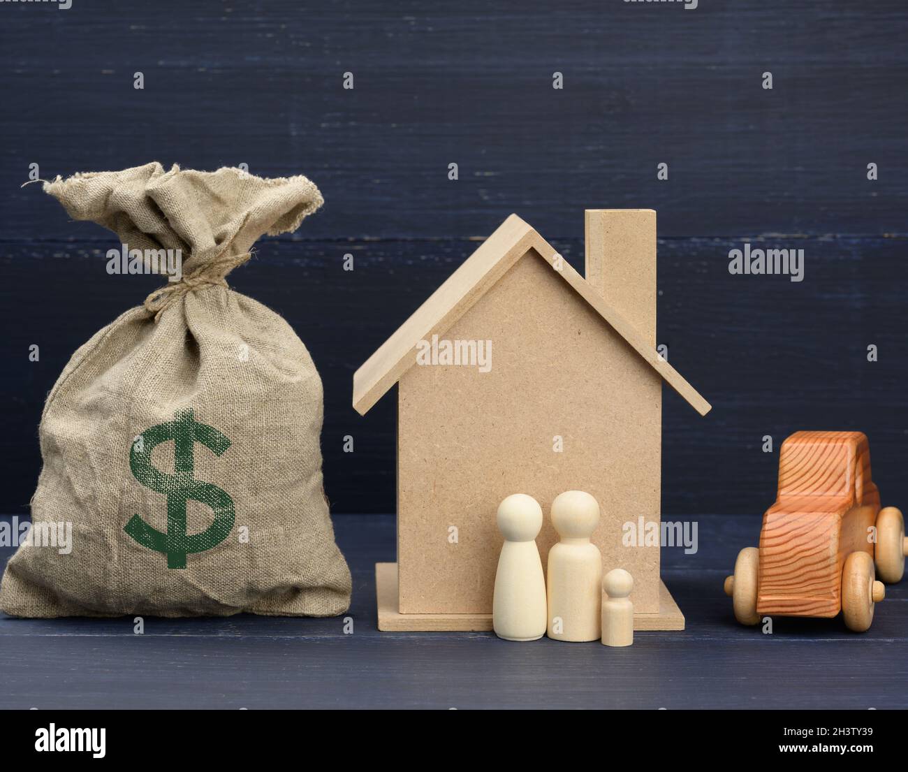 Borsa di tela piena di soldi e una casa di legno su uno sfondo blu. Il concetto di acquisto di immobili Foto Stock