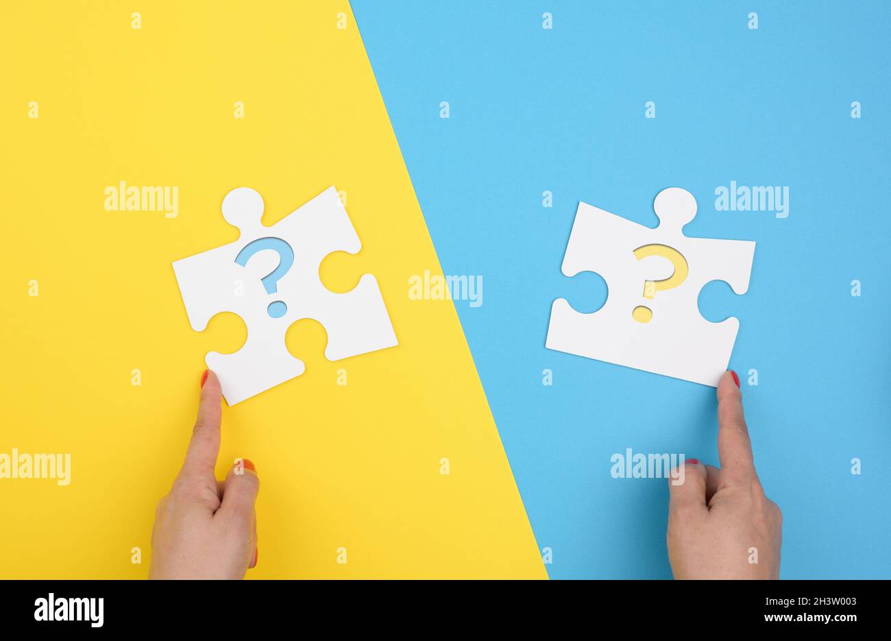 La mano femminile contiene un frammento di un grande puzzle bianco su uno sfondo giallo blu, concetto di trovare un'idea Foto Stock