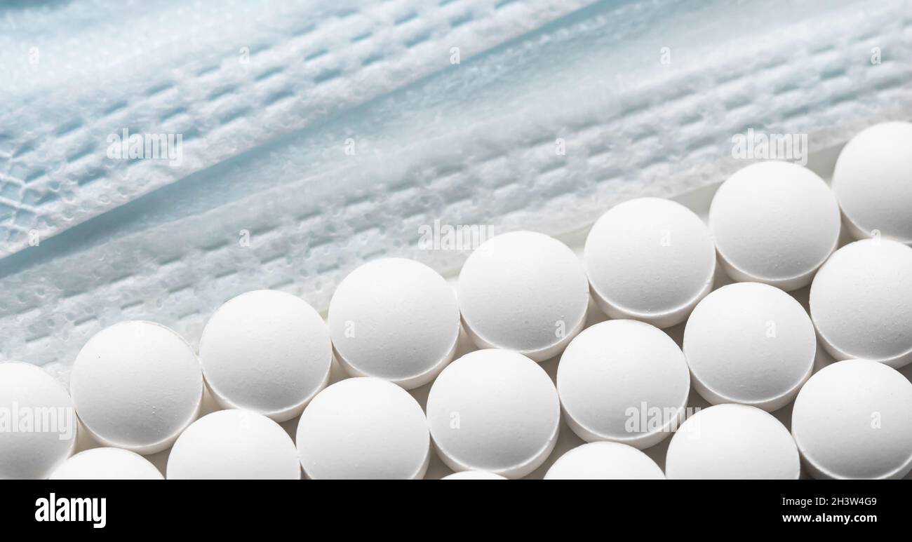 Righe di pillole e maschere mediche su sfondo bianco. Cura della salute, medicina, farmacia e concetto di malattia Foto Stock