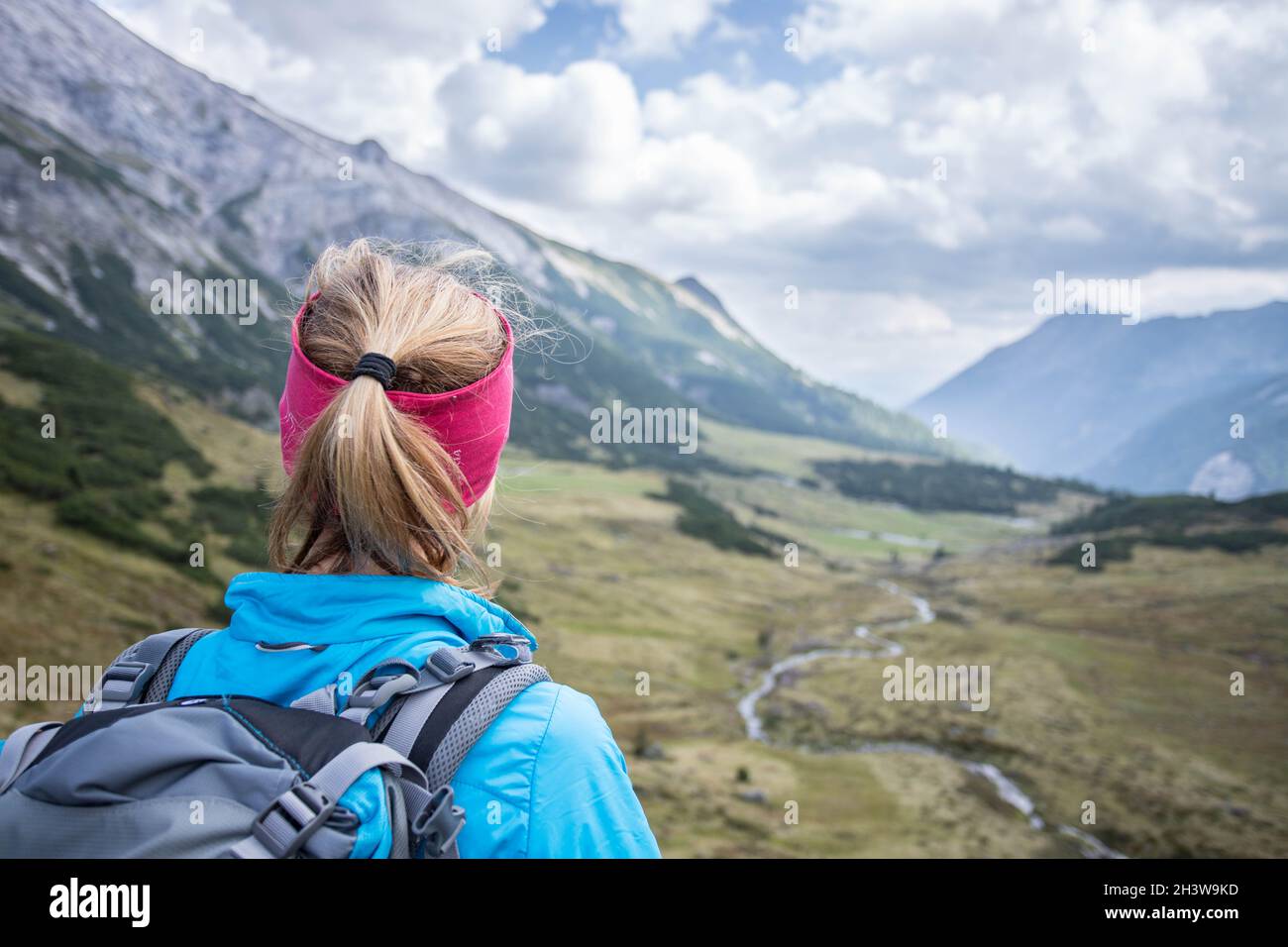 Donna bionda alpinista con zaino è godendo della vista Foto Stock