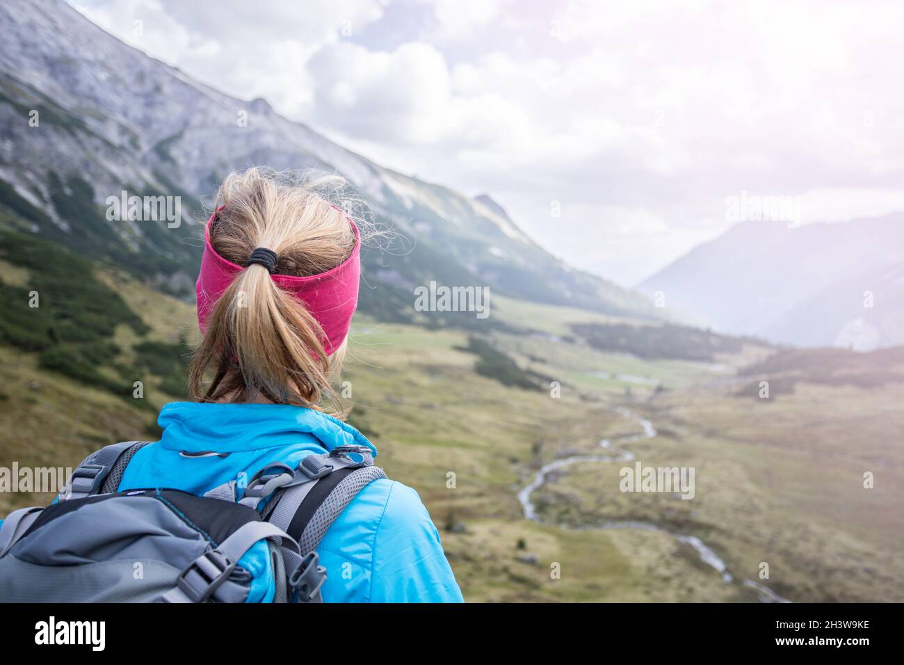 Donna bionda alpinista con zaino è godendo della vista Foto Stock