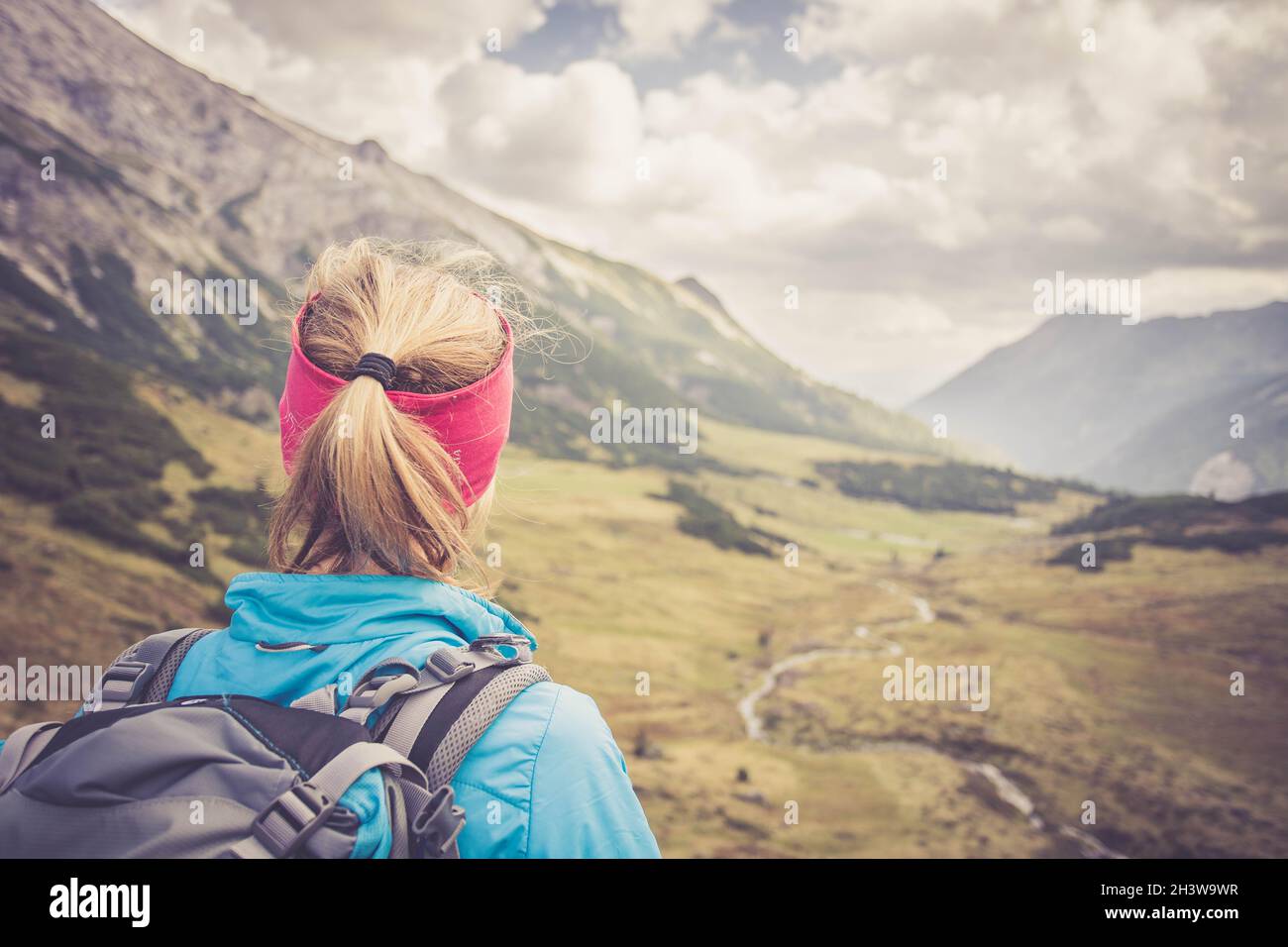Donna bionda alpinista con zaino è godendo della vista Foto Stock