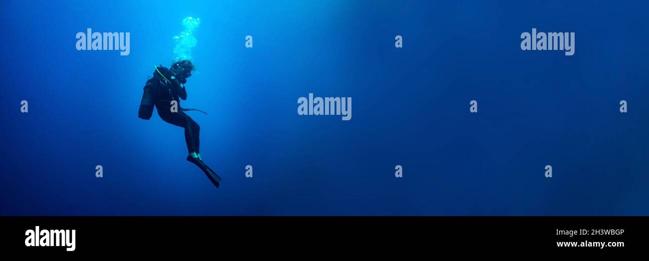 Banner di fondo con una donna subacquea in piedi ancora in blu profondo Foto Stock