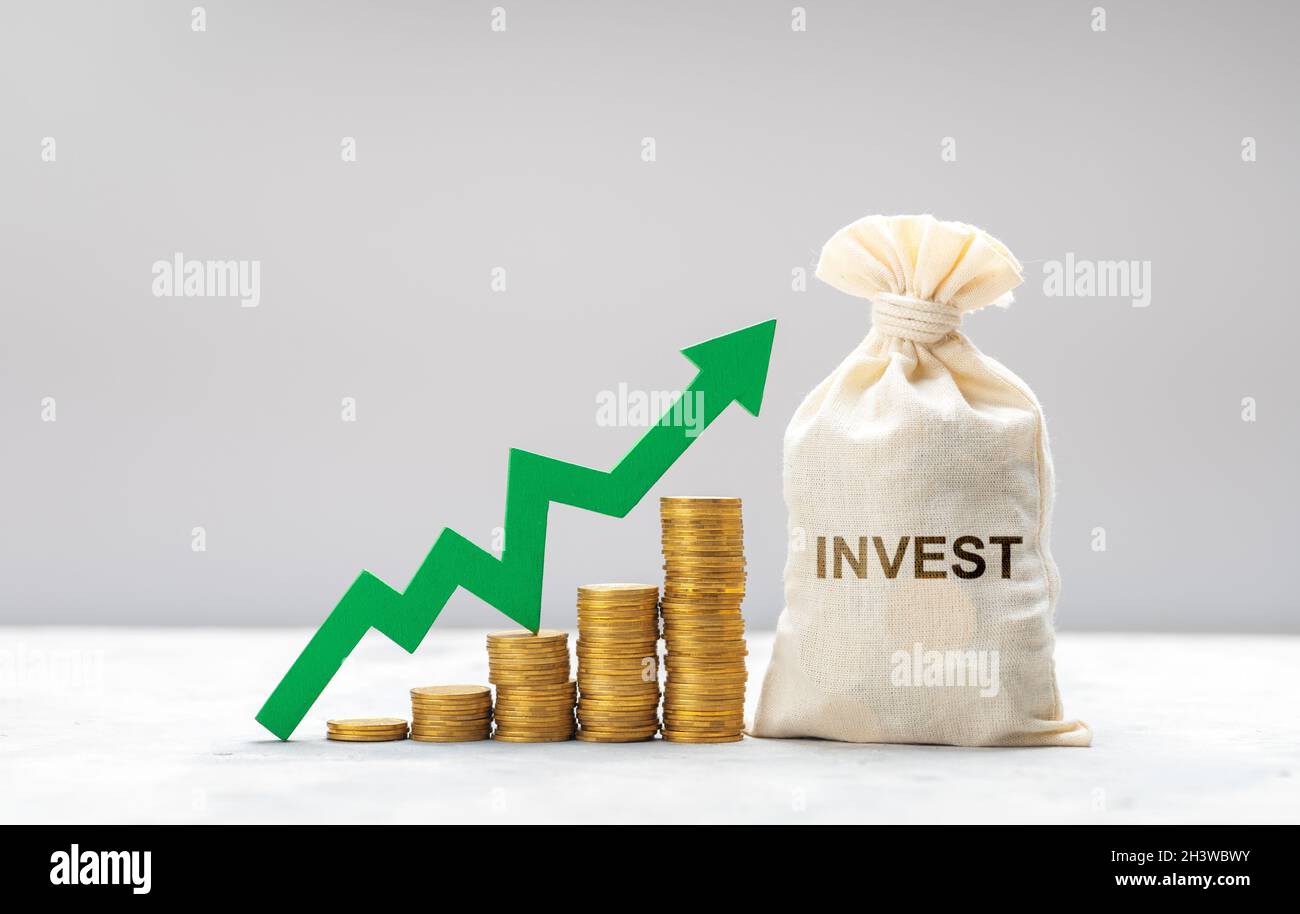 Buon investimento. Freccia verde su monete d'oro e un sacco di soldi come simbolo di investimento. Foto Stock