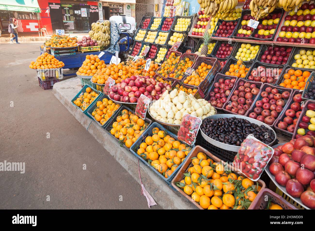 Alessandria d'Egitto - 18 dicembre 2018: Frutta egiziana locale sono su un banco esterno. La gente comune cammina per la strada nelle vicinanze Foto Stock