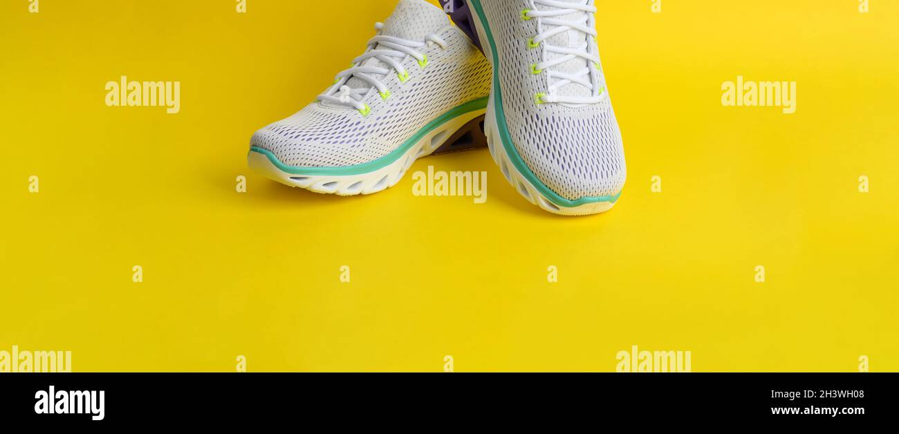 Sneaker bianche da donna con lacci su sfondo giallo Foto Stock