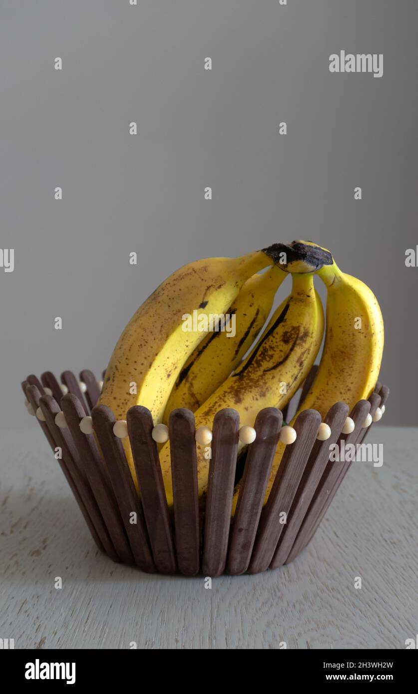 Quattro banane macchiate e macchiate in un cestino Foto Stock