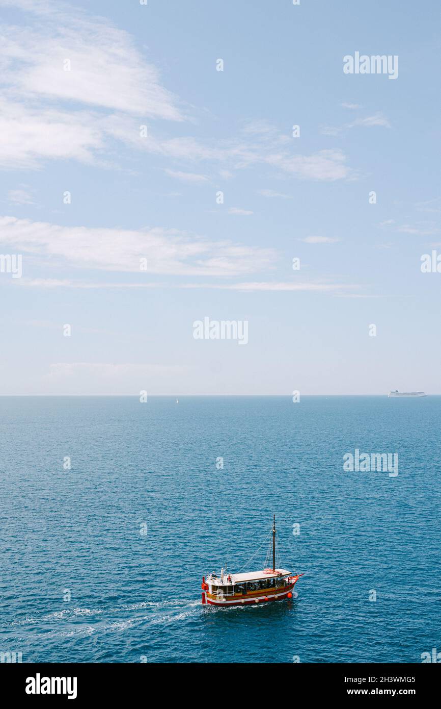 Una piacevole barca rossa naviga sul mare sullo sfondo del cielo e dell'orizzonte. Molto spazio per il testo. Foto Stock