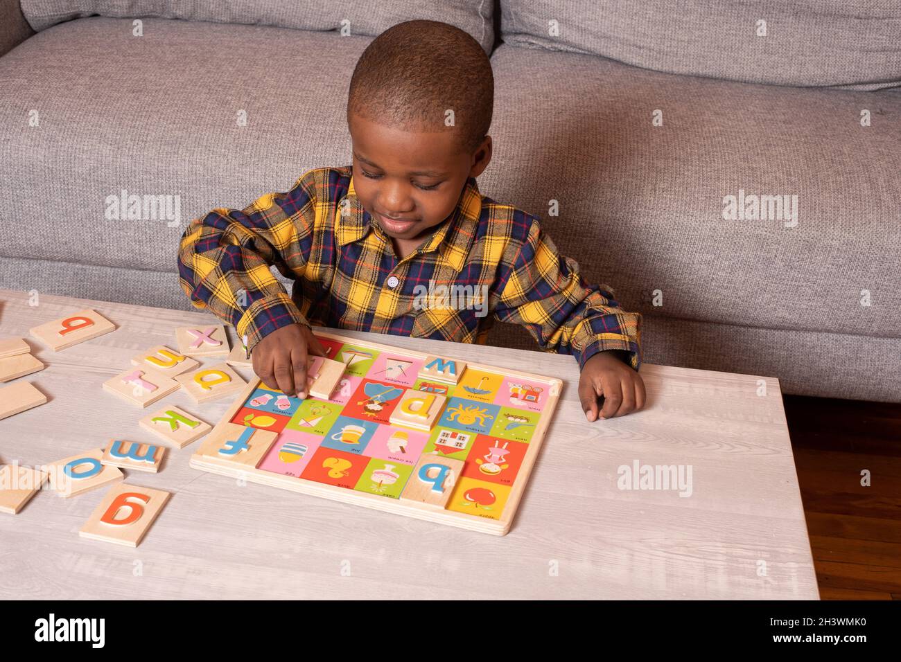 Ragazzo età preschool a casa giocando con puzzle alfabeto Foto Stock