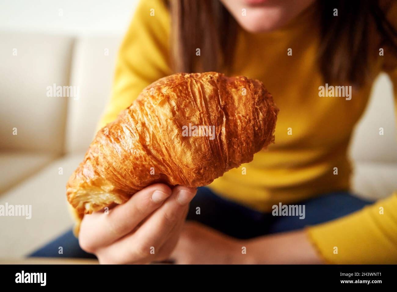Croissant fresco in mano a una ragazza che ha la colazione, da vicino Foto Stock