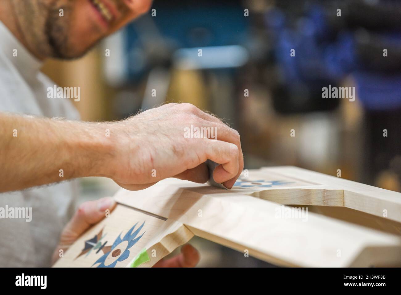 L'uomo sta levigando il legno con la carta di sabbia in parte del processo di fabbricazione del mobile Foto Stock
