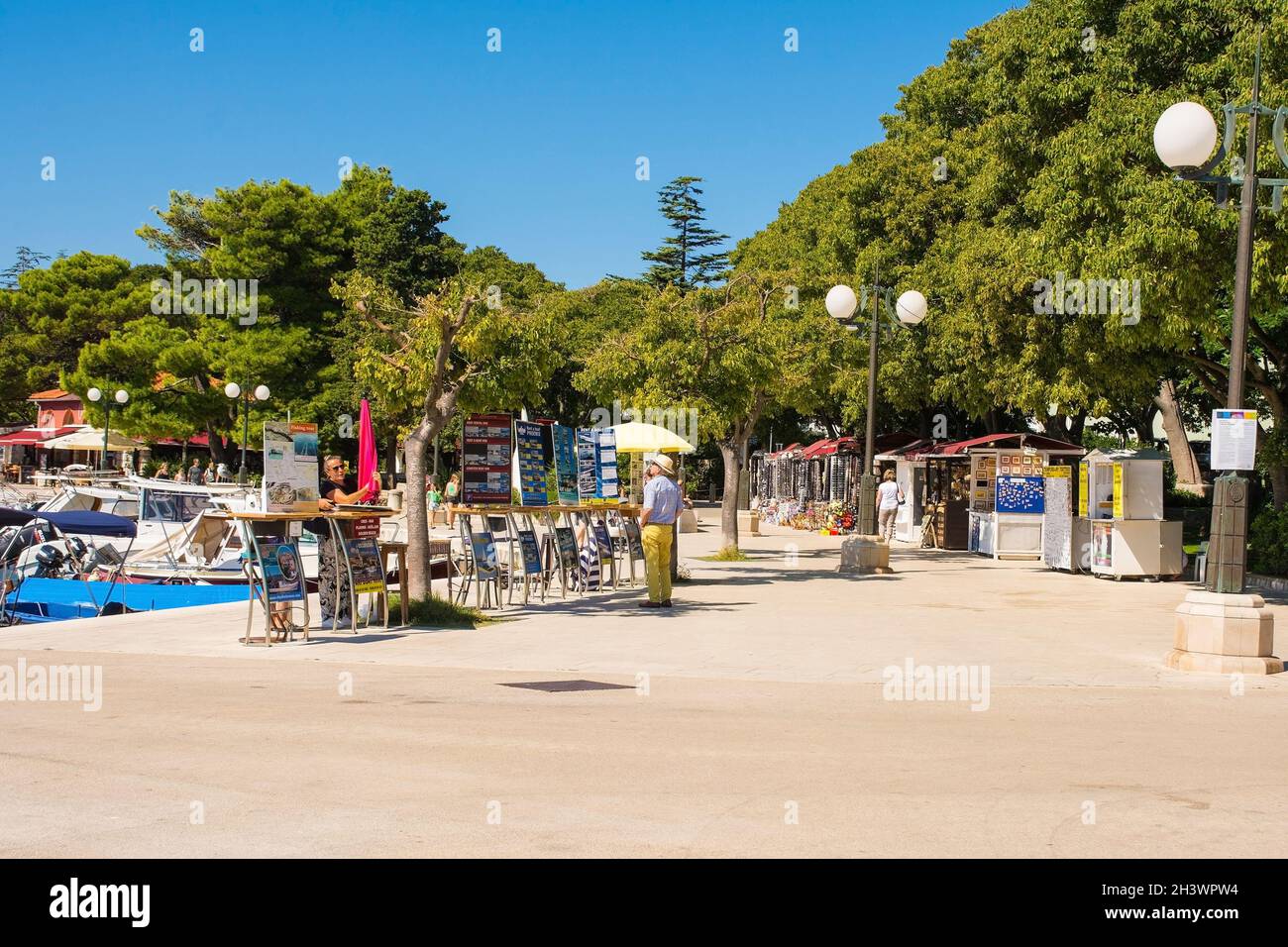 Krk, Croazia - 2 settembre 2021. I venditori di barche sul lungomare aspettano i turisti che passano nella storica cittadina costiera medievale di Krk sull'isola di Krk Foto Stock