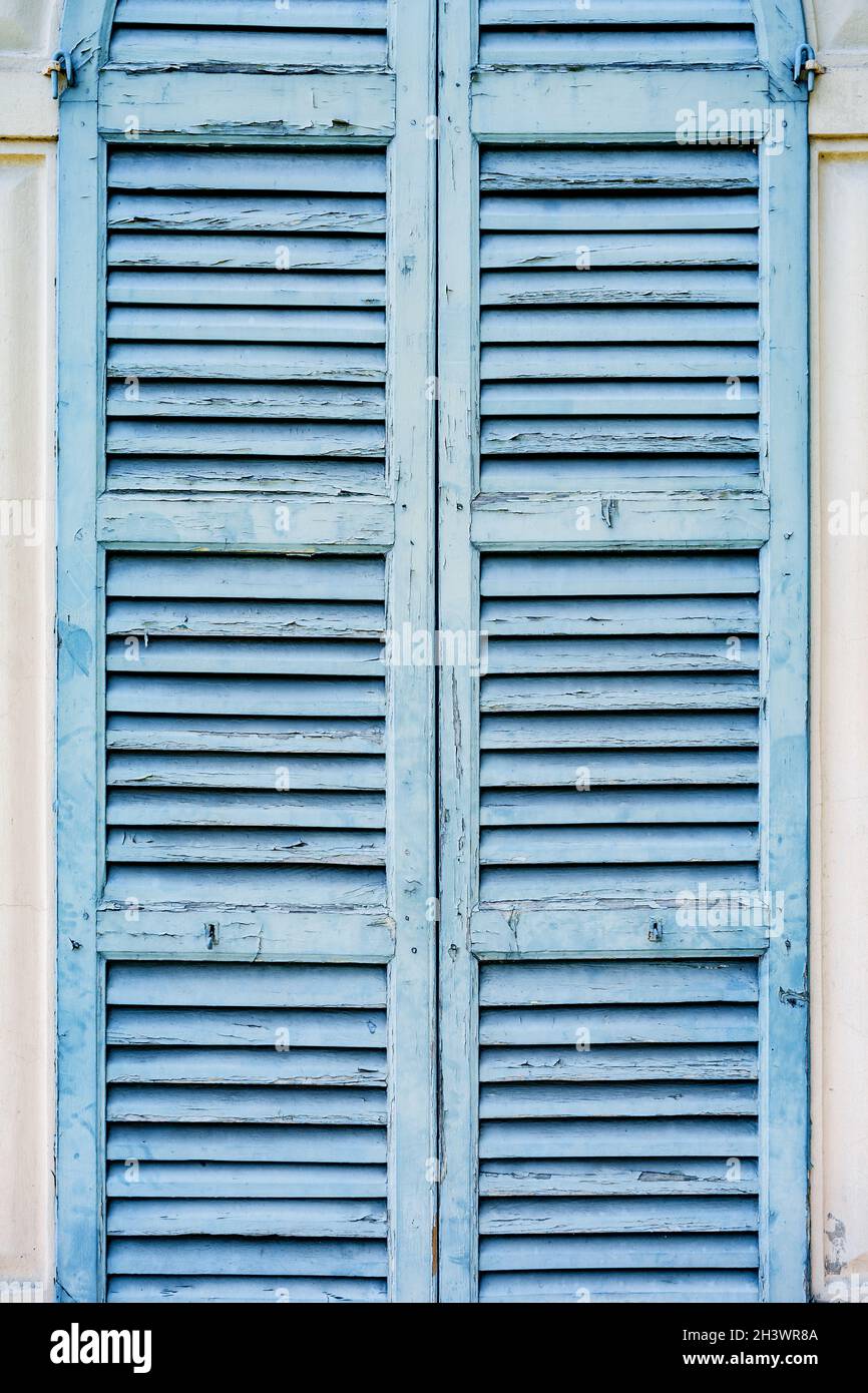 Vecchie persiane blu sulla parete luminosa della casa. Foto Stock