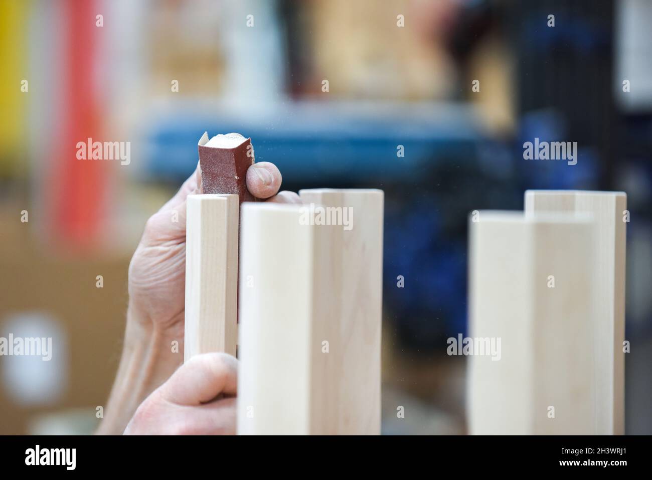 L'uomo sta levigando il legno con la carta di sabbia in parte del processo di fabbricazione del mobile Foto Stock