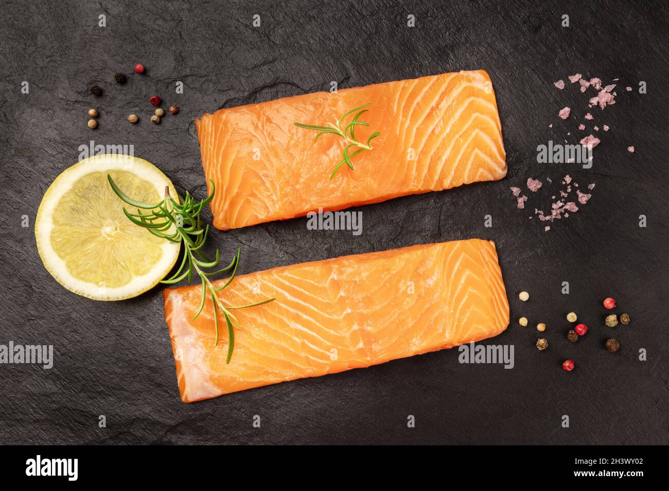 Salmone crudo con spezie su sfondo nero Foto Stock