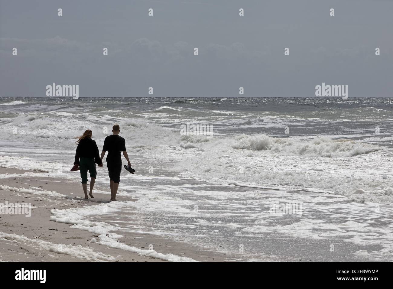Giovani coppie passeggiate sulla spiaggia al surf, Mare del Nord, Hoernum, Sylt, Frisia del Nord, Germania, Europa Foto Stock
