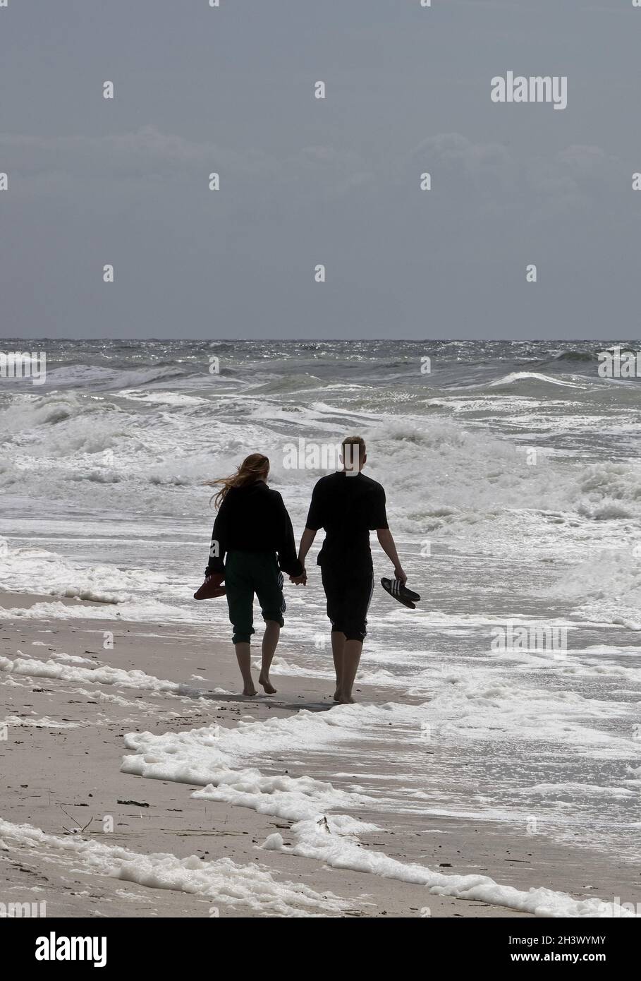 Giovani coppie passeggiate sulla spiaggia al surf, Mare del Nord, Hoernum, Sylt, Frisia del Nord, Germania, Europa Foto Stock