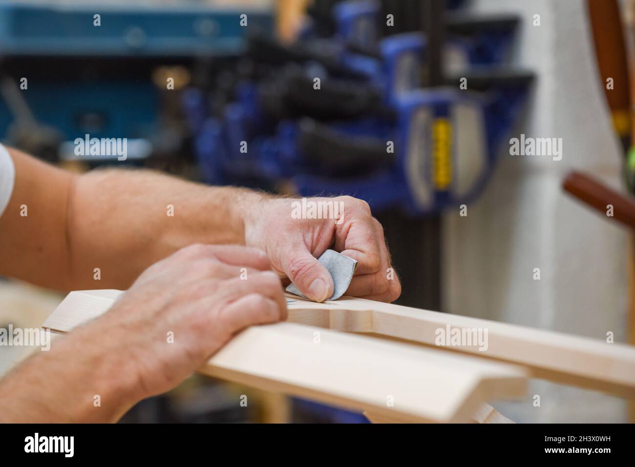 L'uomo sta levigando il legno con la carta di sabbia in parte del processo di fabbricazione del mobile Foto Stock