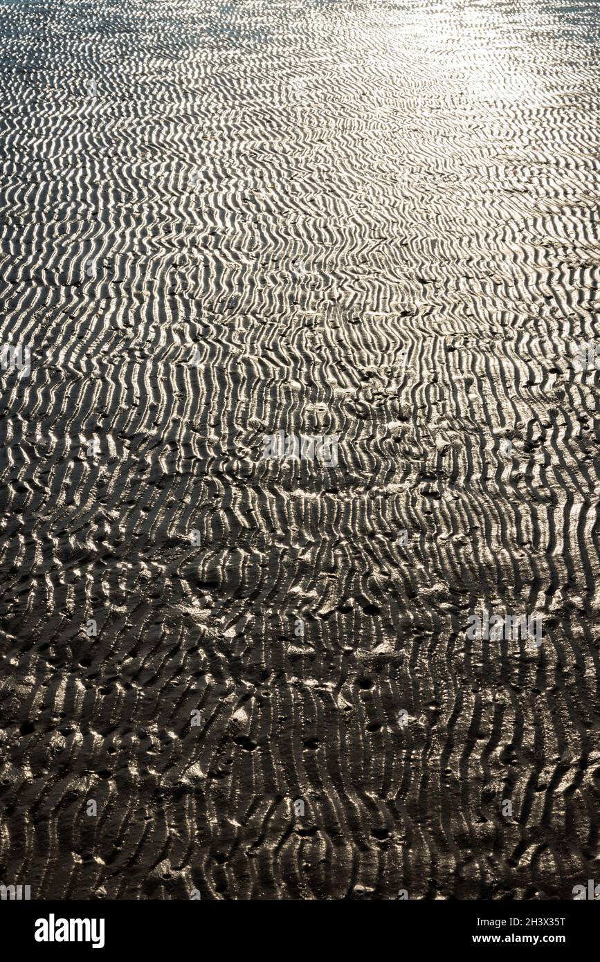 Sfondo di ondate di sabbia sulla spiaggia durante la bassa marea Foto Stock