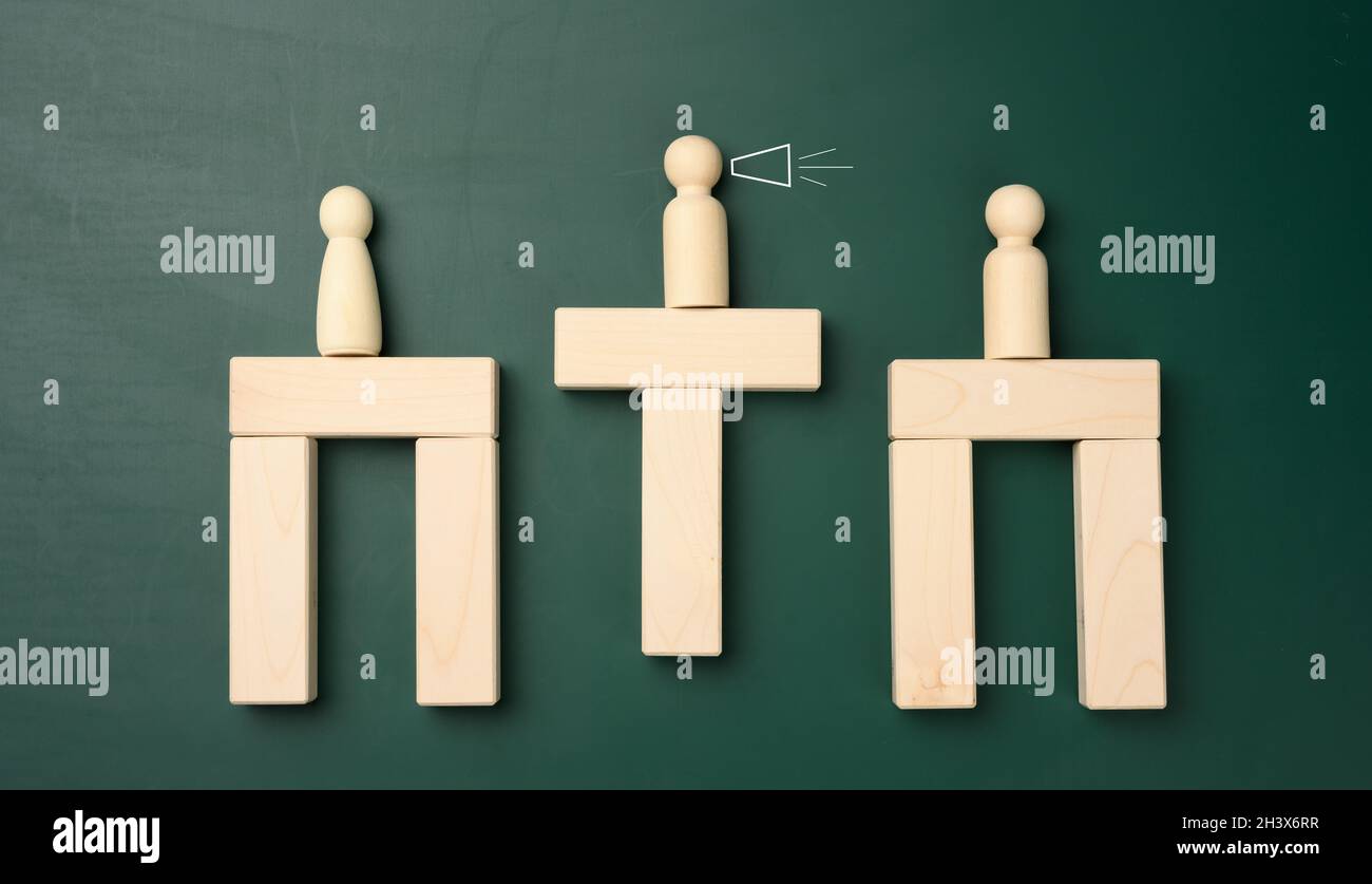 Figure di uomini in legno su un ponte di sbarre, al centro c'è un negoziatore. Foto Stock